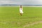 Beautiful young girl in a white dress with long hair on the field on a cloudy day