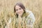 Beautiful young girl in a white sweater sits in a wheat field