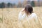 Beautiful young girl in a white sweater sits in a wheat field