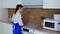 Beautiful young girl wipes an electric stove in pink gloves for cleaning.