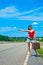 Beautiful young girl or woman in mini with suitcase hitchhiking along a road