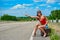 Beautiful young girl or woman in mini with suitcase hitchhiking along a road