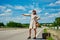 Beautiful young girl or woman in mini with suitcase hitchhiking along a road - retro style