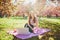 Beautiful young girl working on her laptop in park during cherry blossom season