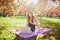 Beautiful young girl working on her laptop in park during cherry blossom season