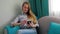 Beautiful young girl working on a smartphone sitting on a sofa in the room