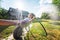 Beautiful young happy woman hosing garden, summer splashes eco-friendly lifestyle