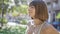 Beautiful young hispanic woman breathing, relaxing, meditating in sunny green park, closing eyes, enjoying air and positive calm