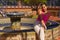 Beautiful young Hispanic woman sitting on the border of an old Andalusian fountain without working. Rest concept