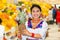 Beautiful young hispanic woman wearing andean traditional blouse posing for camera holding pineapple inside fruit market