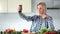 Beautiful young housewife taking selfie using smartphone at kitchen during cooking healthy food
