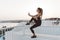 Beautiful young joyful woman in sportswear with long curly hair making selfie on seafront on sunrise background