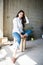 Beautiful young lady artist in white shirt sitting barefoot in her bohemian artistic studio loft