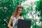 Beautiful young lady looks at a big black notebook amid trees