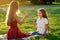 Beautiful and young long-haired woman playing with her daughter in a summer day in the park . happy motherhood and a