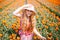 Beautiful young long red hair woman wearing in striped dress and straw hat standing on colorful flower tulip field in Holland