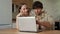 Beautiful young married couple uses a laptop together at home in the kitchen. A happy young couple pays bills online in