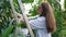Beautiful young millennial woman gathering cherries from tree branch in summer garden. Side view portrait of confident