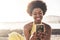 Beautiful young model girl black rac african hair use mobile phone technology to write friends during a vacation. ocean and