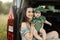 Beautiful young mother with dark hair embracing her cute little daughter on green dress on hands