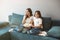 Beautiful young mother with her cute teenager daughter watching cartoon on the sofa eating popcorn