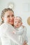 A beautiful young mother holds in her arms a small pretty blue-eyed 2-month-old daughter. Newborn