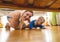 Beautiful young mother with toddler boy lying on floor and looking under the bed