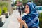 Beautiful young muslim woman wearing blue colored hijab, folding hands performing prayer, outdoors urban background