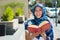 Beautiful young muslim woman wearing blue colored hijab, holding thick reed book and reading in street, outdoors urban