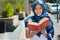 Beautiful young muslim woman wearing blue colored hijab, holding thick reed book and reading in street, outdoors urban