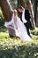 Beautiful young newly wed couple leaning against tree trunk in forest