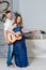 Beautiful young pregnant woman with her husband fun playing guitar. A couple in anticipation of a child rejoices and laughs