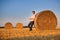 Beautiful young pregnant woman relaxing in a hay bales field