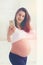 Beautiful young pregnant woman taking selfie on smart phone