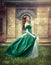 Beautiful, young, red-haired girl in a green medieval dress, climbs the stairs to the castle.