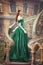 Beautiful, young, red-haired girl in a green medieval dress, climbs the stairs to the castle. Fantastic photosession.