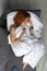Beautiful young red-haired girl sleeps on the sofa, bypassing white blanket. Top view