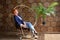 Beautiful young red-haired woman sits on a metal round chair and looks away thoughtfully