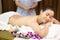 Beautiful young relax Asian woman laying on massage bed with naked back body, masseur prepare oil massage at back side at spa