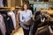 Beautiful young saleswoman helps the customer to choose a jacket in suit shop.