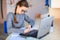 Beautiful young school girl left-handed working at home in her room with a laptop and class notes studying in a virtual class.