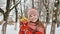 A beautiful young schoolgirl standing in a snowy forest in the winter takes a joyful gift from the hands of a friend.