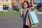 Beautiful young shopaholic Asian woman using smartphone for talking while she walking to buy cosmetics, clothes etc.