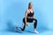 Beautiful young slim fit woman doing lunge exercise with yellow dumbbells