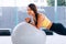 Beautiful young smiling Asian woman training pilates, yoga plank at gym with exercise ball