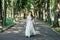 Beautiful young smiling brunette bride in wedd dress with bouquet of flowers in hands goes in the park outdoors
