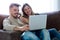 Beautiful young smiling couple using their laptop at home.