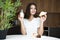 Beautiful young smiling woman feeling hungry holding croissant and glass of kefir for breakfast in the kitchen looking