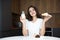 Beautiful young smiling woman feeling hungry holding croissant and glass of milk for breakfast in the kitchen looking