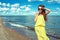 Beautiful young smiling woman wearing yellow striped baggy summer maxi dress at the seaside